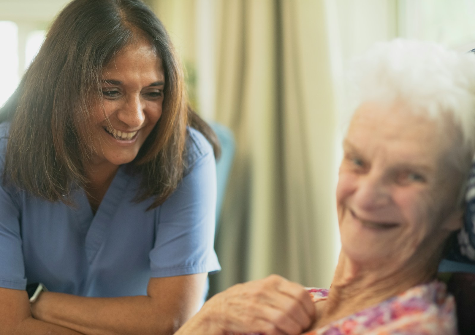 Nurse smiling with an elderly patient in a room